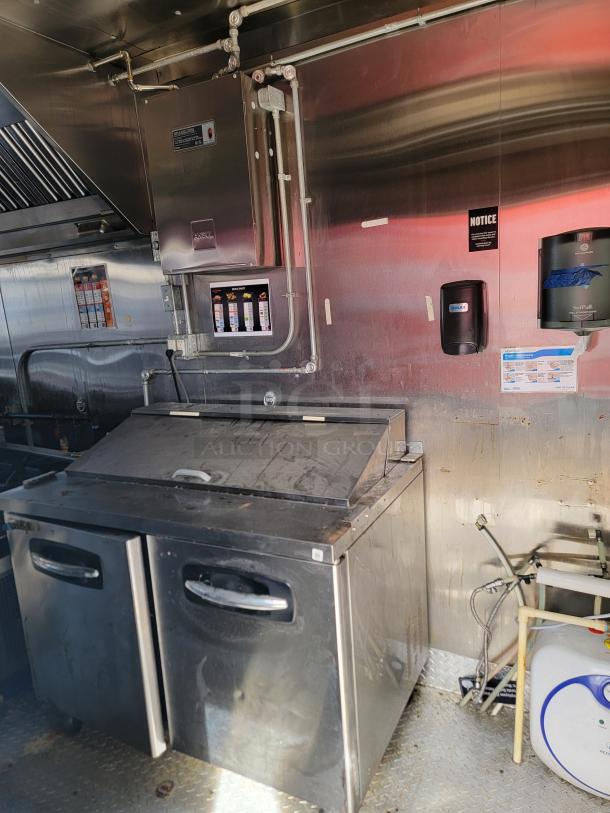 Commercial stainless steel kitchen setup with two-door under-counter refrigerator and Ansul fire suppression system.