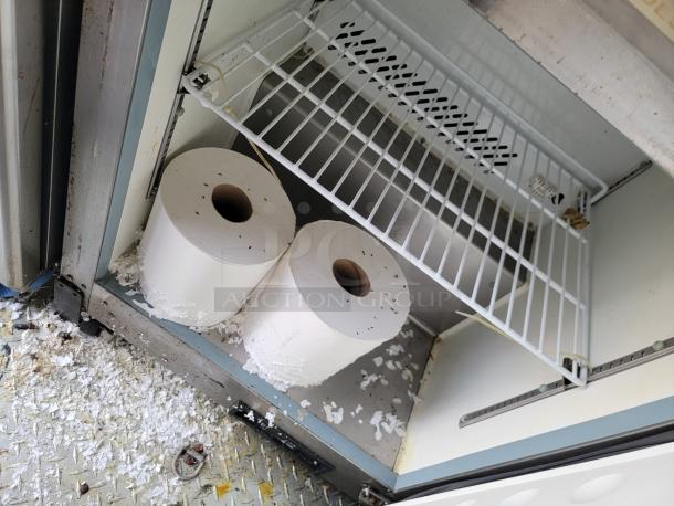 Two large rolls of paper in an open metal cabinet, with shredded paper on the floor and shelf above. Condition appears used.