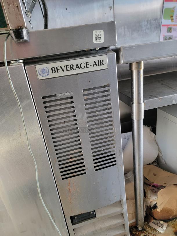 Beverage-Air refrigeration unit, stainless steel, front vents, visible wear, visible QR code, used condition.