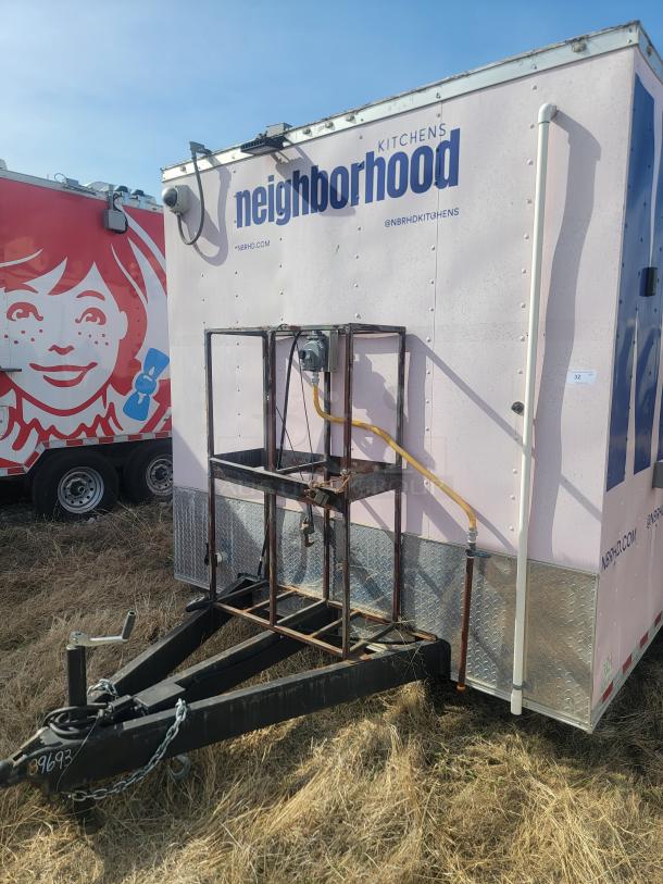Mobile kitchen trailer branded "Neighborhood Kitchens" in used condition, visible tow bar, with website and social handles displayed.