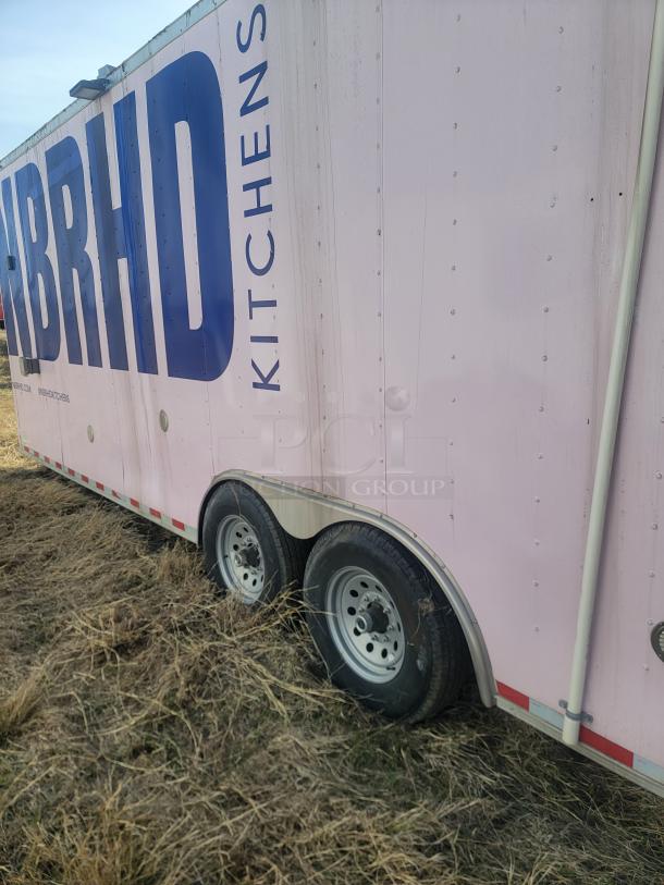 Pink cargo trailer with dual axles and the text "KITCHENS" and partially visible "BRHD" on the side. Appears used.