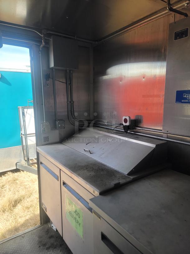 Industrial metal food delivery unit with compartments, visible wear, and electrical wiring. Sticker on front reads "X FOOD DELIVERY."