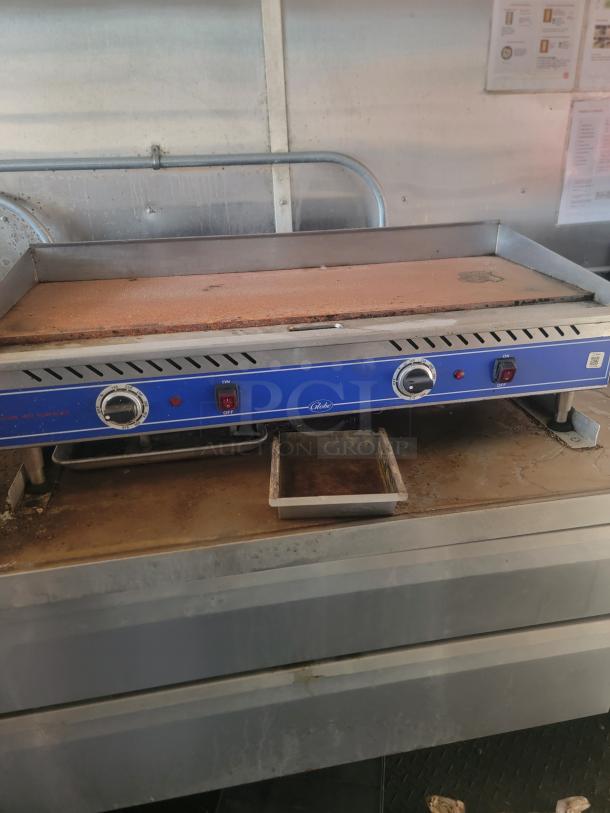 Commercial flat top grill with dual temperature controls and grease tray. Shows signs of use; suitable for restaurant kitchens.