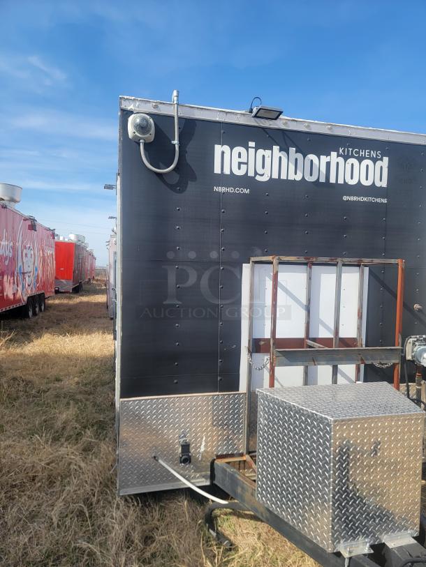 Mobile kitchen trailer with "Neighborhood Kitchens" branding, featuring diamond plate exterior, and utility connections. Signs of outdoor wear.