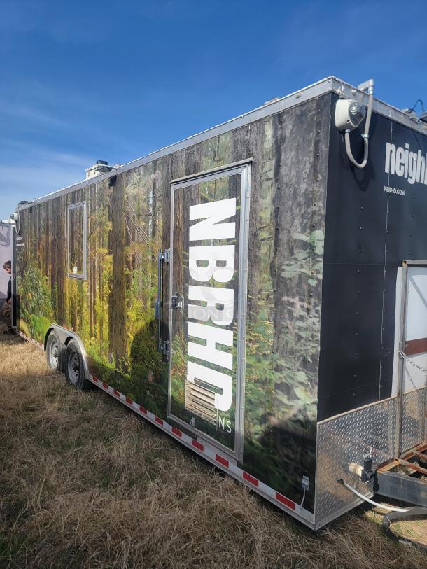 Mobile trailer with forest mural and "NBRHD" branding. Features side door, windows, and roof equipment. Good condition.