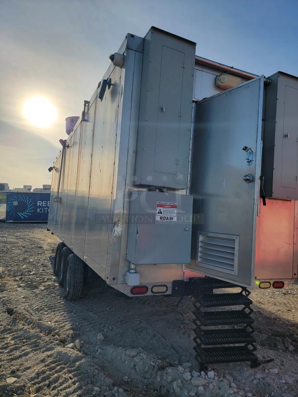 Industrial mobile trailer with metal exterior, rear stairs, visible electrical panel. Appears in fair condition with minor wear.