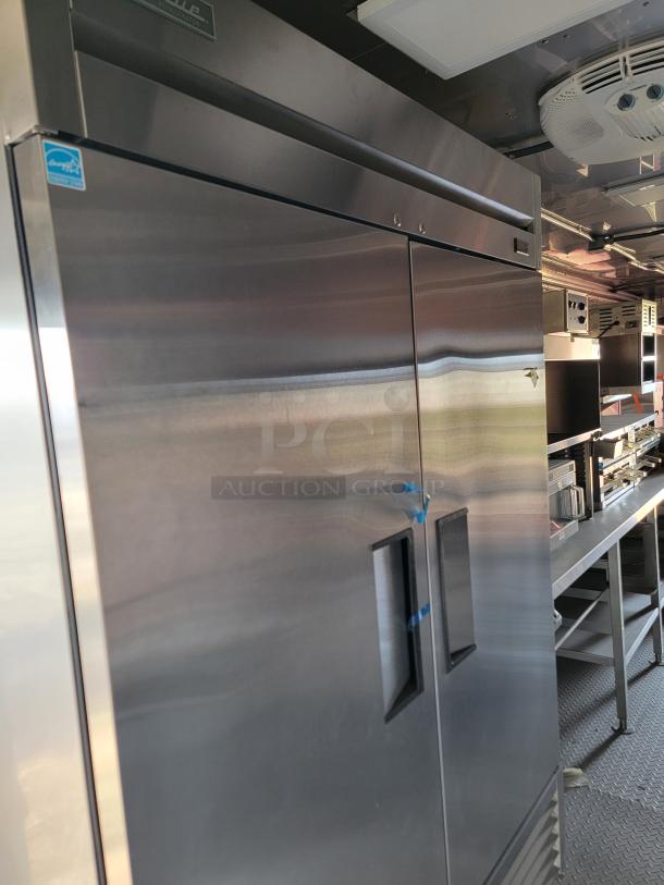 Commercial stainless steel refrigerator, dual-door, True brand with visible branding sticker, excellent condition.