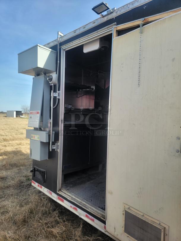 Mobile kitchen trailer with open door, revealing stainless steel interior, storage cabinets, and industrial equipment. Good condition.