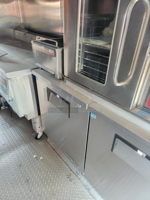 Industrial stainless steel oven and refrigerator in a kitchen setting, featuring glass oven door and sturdy construction.