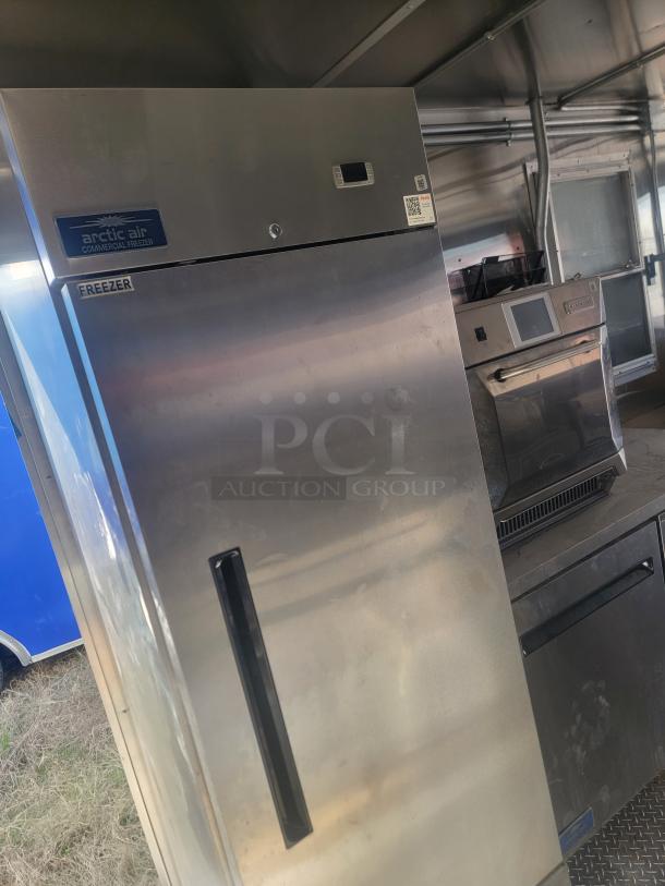 Arctic Air commercial freezer, stainless steel, upright model, labeled "freezer," shows minor wear, ideal for food storage.