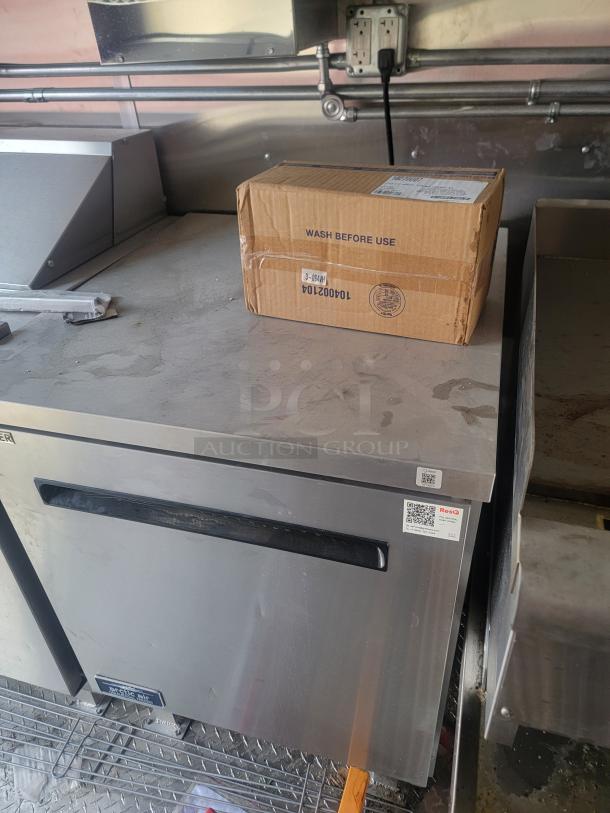 Stainless steel industrial freezer with black handle, in good condition. Box marked "Wash Before Use" on top. QR codes visible.