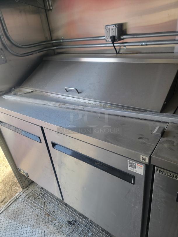 Stainless steel commercial refrigerator with dual doors, minor surface marks, and QR code labels; ideal for kitchen setups.