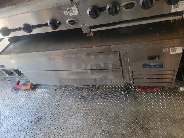 Commercial kitchen equipment, stainless steel Wells grill and Arctic Air refrigeration unit, used, visible wear.