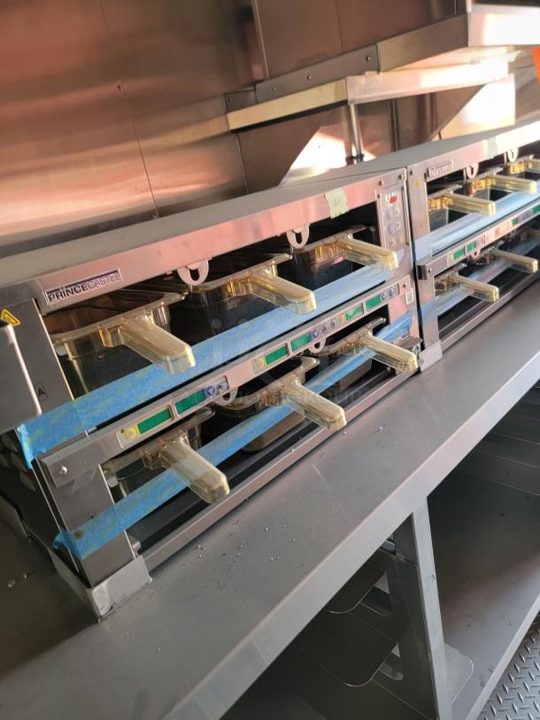 Commercial sandwich toaster with three slots, Prince Castle brand. Stainless steel, like-new condition, protective tape intact.