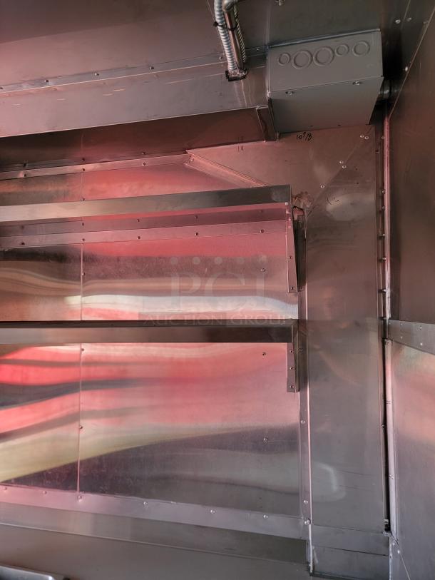 Metallic industrial ductwork with reflective panels and visible screws, showing structural angles and a marked date "10/3".