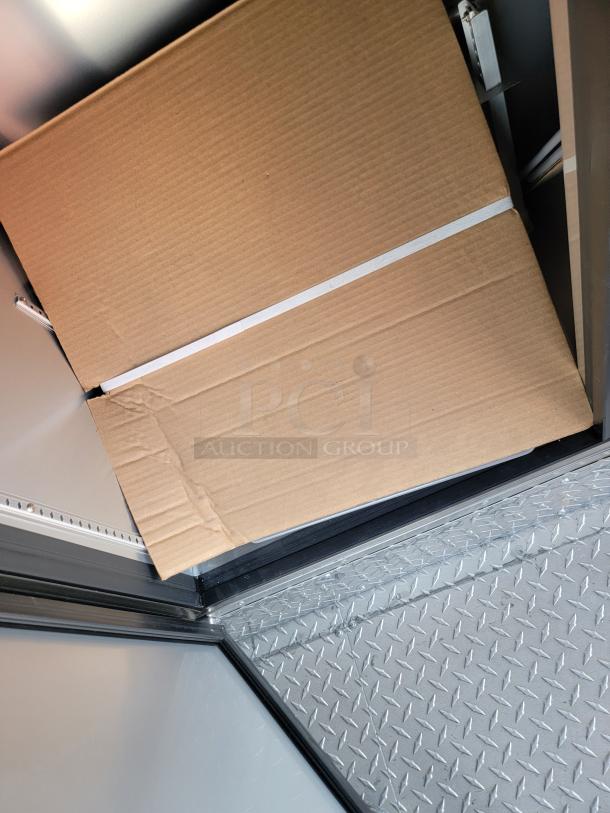 Cardboard box with white tape on metal diamond plate flooring, no visible markings or labels. Boxes may contain auction items.