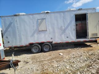 Mobile trailer with dual axles in fair condition, featuring an open door, rooftop vents, and external utility connections.