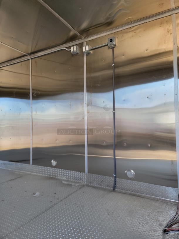 Industrial metal interior with diamond plate flooring, conduit wiring, and power outlets; clean and well-maintained condition.