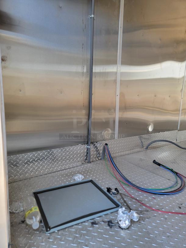 Interior of a metal trailer with diamond plate flooring, multi-colored cables, and a screen panel. Condition appears used.