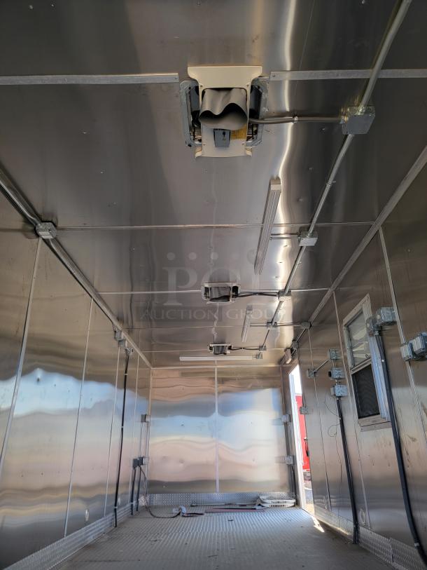 Interior view of a metal trailer with electrical installations, overhead vents, and fluorescent lighting. Clean condition.