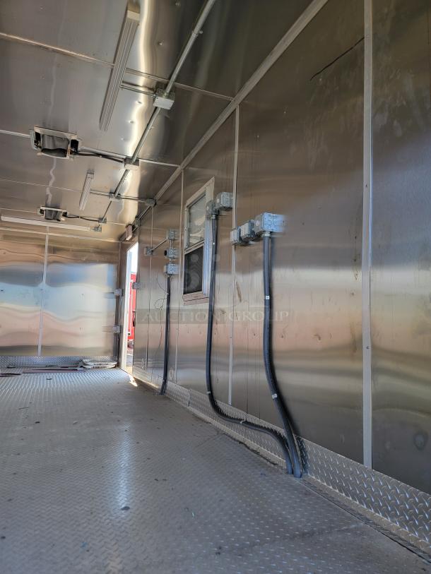 Interior of a metal utility trailer with wiring conduits, wall outlets, and diamond plate flooring, in good condition.