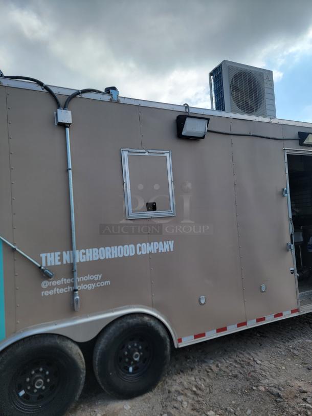 Mobile business trailer by "The Neighborhood Company"; features rooftop HVAC unit, side vents, and branded text, in good condition.