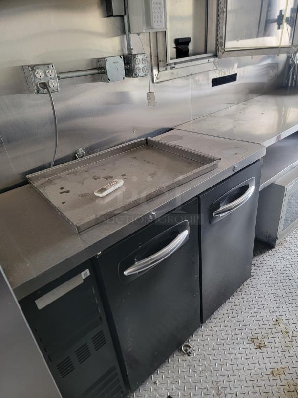 Commercial stainless steel prep station with two black refrigeration units, control panel, and outlets; used condition.