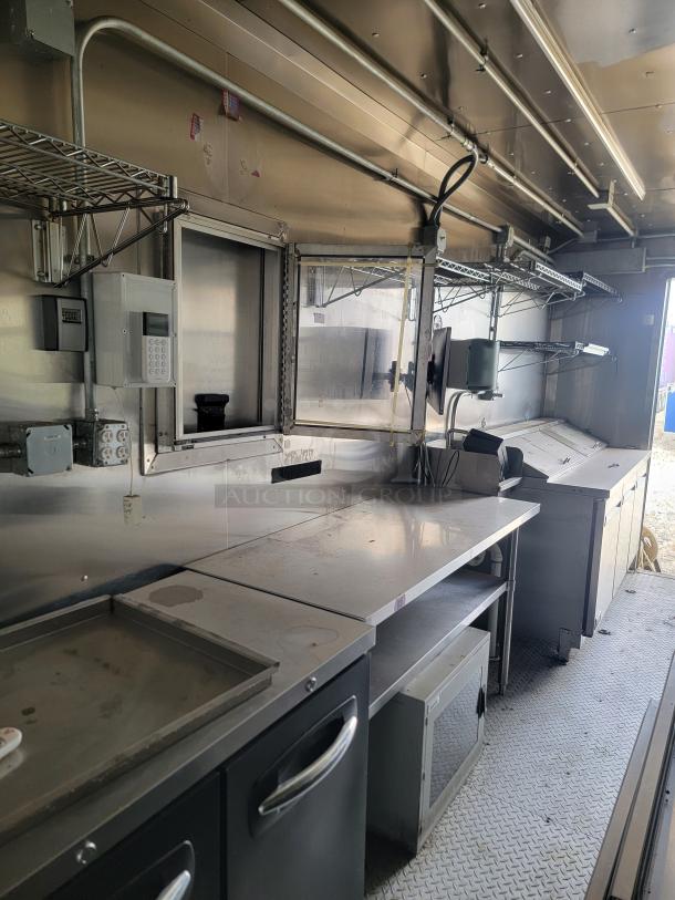 Industrial stainless steel kitchen unit with metallic shelves, counter space, and storage cabinets. Suitable for food service use.
