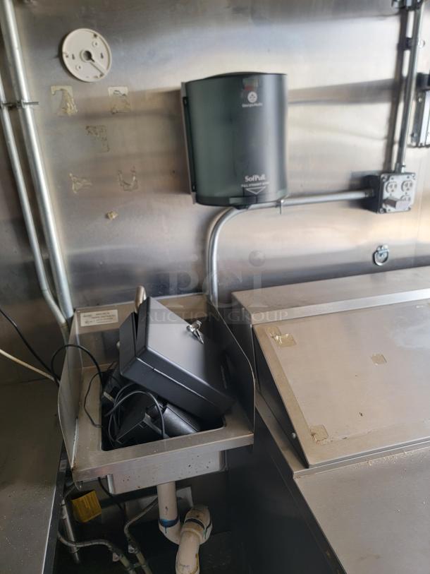 Commercial kitchen wall with a mounted Georgia-Pacific SofPull paper towel dispenser. Stainless steel surfaces and electrical outlets visible.