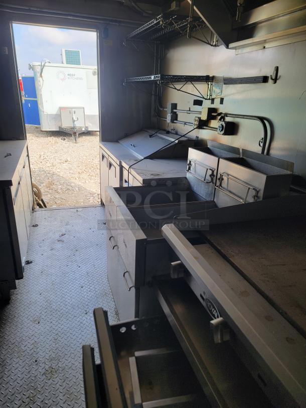 Mobile kitchen interior with grill, fryer, and shelving. Visible "Reef Kitchens" logo outside. Good condition.