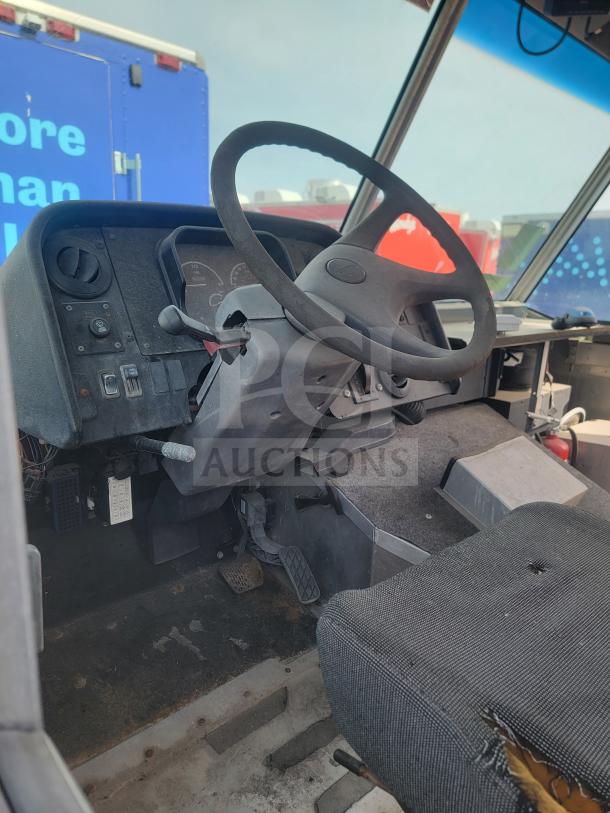 Interior view of 2013 Freightliner MT45 mobile kitchen, showing steering wheel, dashboard, pedals, and worn driver's seat.
