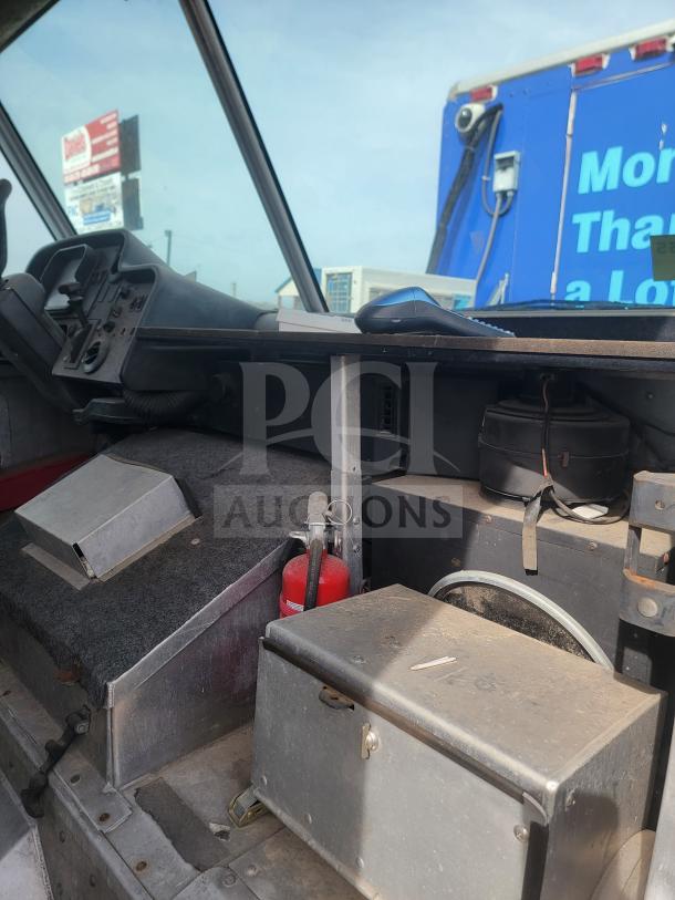 Interior view of 2013 Freightliner MT45 mobile kitchen, showing driver's area with controls, fire extinguisher, and storage box.
