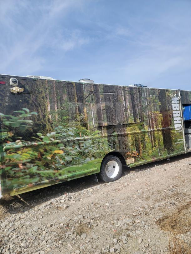 2013 Freightliner MT45 22' mobile kitchen with forest-themed wrap, features Arctic Air refrigeration, Hoodz ventilation, and Cummins engine.