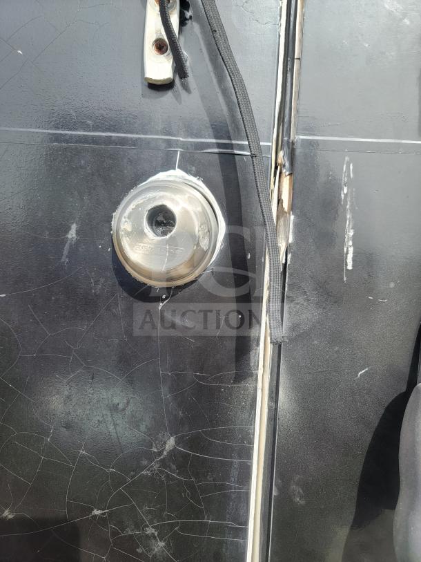 Close-up of a 2013 Freightliner MT45's exterior, showing a round metal fuel cap with wear on a black, cracked surface.