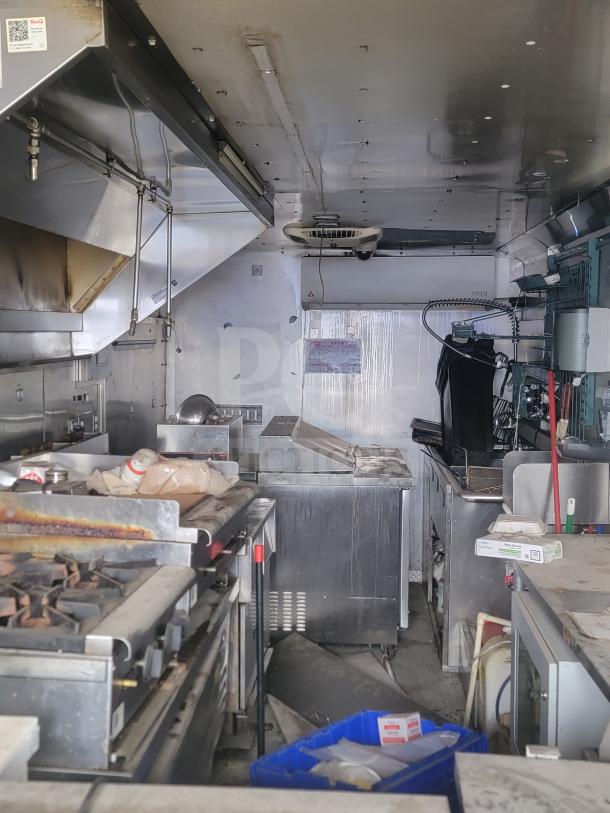 Interior of a 2013 Freightliner MT-45 mobile kitchen, featuring Arctic Air refrigeration and Hoodz ventilation, showing cooking appliances and workspace.