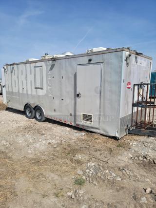 Mobile kitchen trailer, labeled "NBRHD Kitchens," in used condition. Features dual axles, rooftop ventilation, and side entry door.