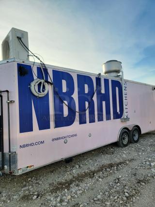 Mobile kitchen trailer by NBRHD Kitchens, featuring dual axles, rooftop equipment, and brand markings. Good condition.