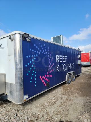 Mobile kitchen trailer branded "REEF KITCHENS," features dual axles and vibrant exterior. Good condition.