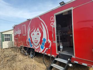 Red Wendy's food truck featuring the company logo, partially open, with visible kitchen equipment inside. Good condition.