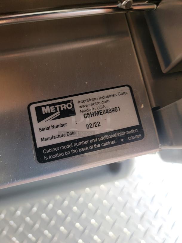 Metallic item label showing "Metro" brand, serial number C5HME043961, made in USA, manufactured 02/22.