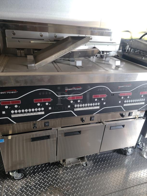 Henny Penny commercial fryer, stainless steel, digital controls, dual compartments, good condition, "Caution Hot" label visible.