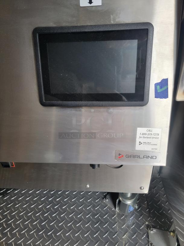 Stainless steel Garland kitchen appliance with touchscreen display. Label reads "Call 1-800-379-7278 for Garland service."