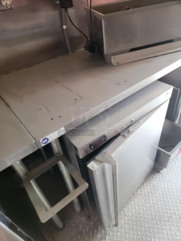 Commercial stainless steel kitchen equipment, includes countertop, bins, and cooling unit. Used condition, slight wear visible.