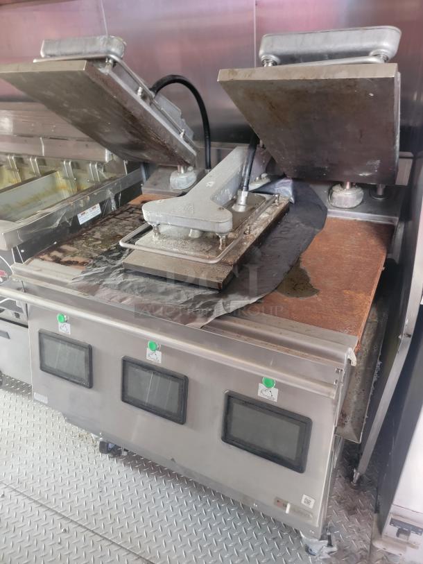 Industrial panini press with dual top plates, in used condition showing wear. Control buttons and display screens visible.