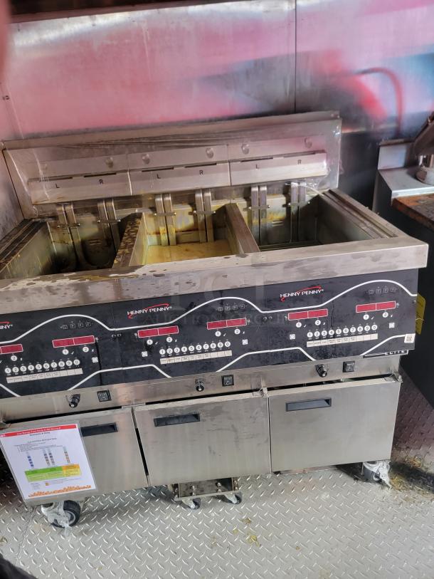 Henny Penny fryer with multiple compartments, digital controls, and stainless steel exterior. Used condition with visible signage.