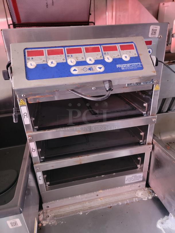 Electronic food holding unit by Prince Castle, multiple compartments, button controls, visible wear, suitable for commercial use.