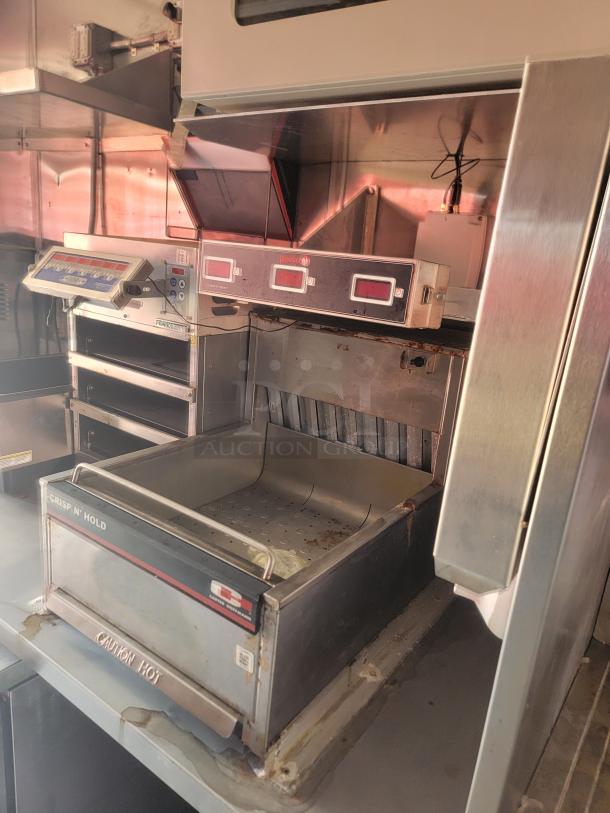 Commercial kitchen equipment with “Crisp N’ Hold” label, stainless steel construction, features control buttons and a caution hot warning.