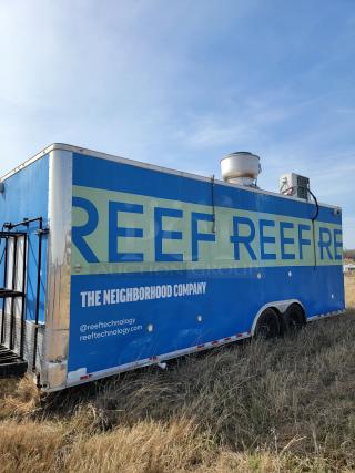 Blue mobile kitchen trailer with "Reef Technology" branding. Visible wear on sides. Equipped with ventilation and AC units.