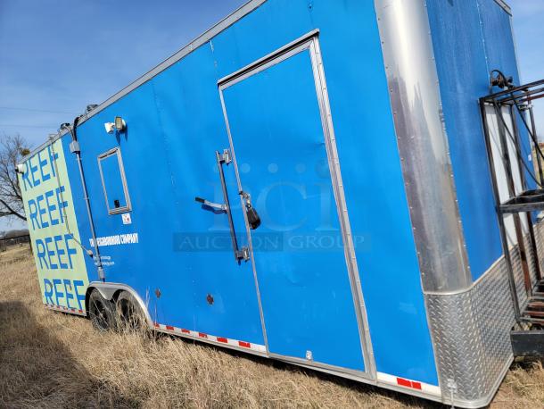 Blue mobile trailer, "REEF" branding, dual axle, side door, used condition, diamond plate trim, The Neighborhood Company label.