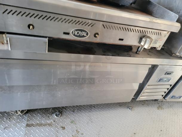 Stainless steel Royal commercial kitchen equipment, featuring storage compartments, signs of wear, and visible brand logo.